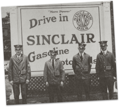 Gas station attendants in front of sinclair oil sign
